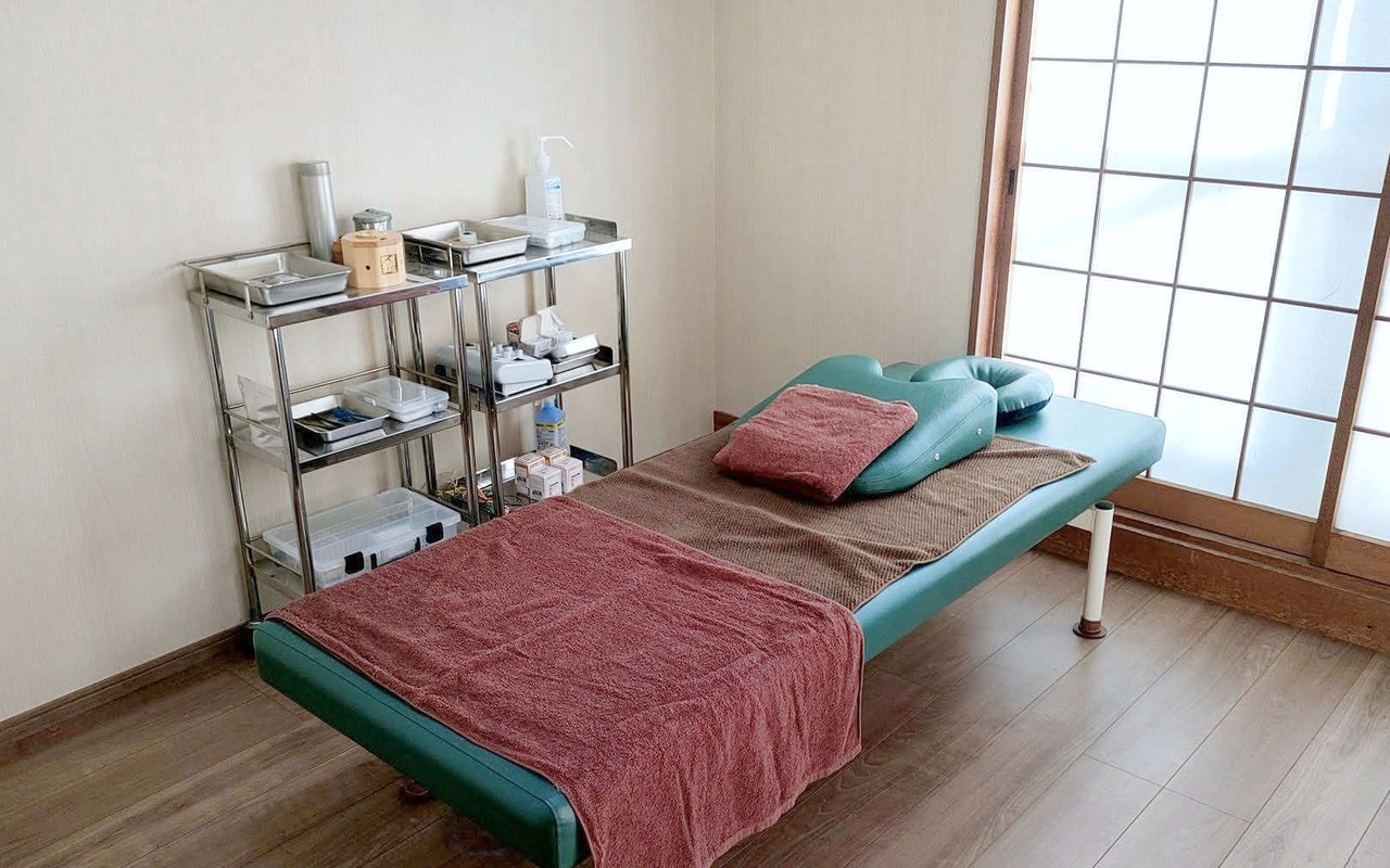 施術室。障子から光の入る和室にベッドが置かれている